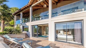 Une maison moderne dotée d’une piscine, d’un espace salon extérieur et de grandes fenêtres.