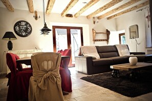 Una sala de estar con techo de madera, un sofá, una mesa de centro y un reloj en la pared.