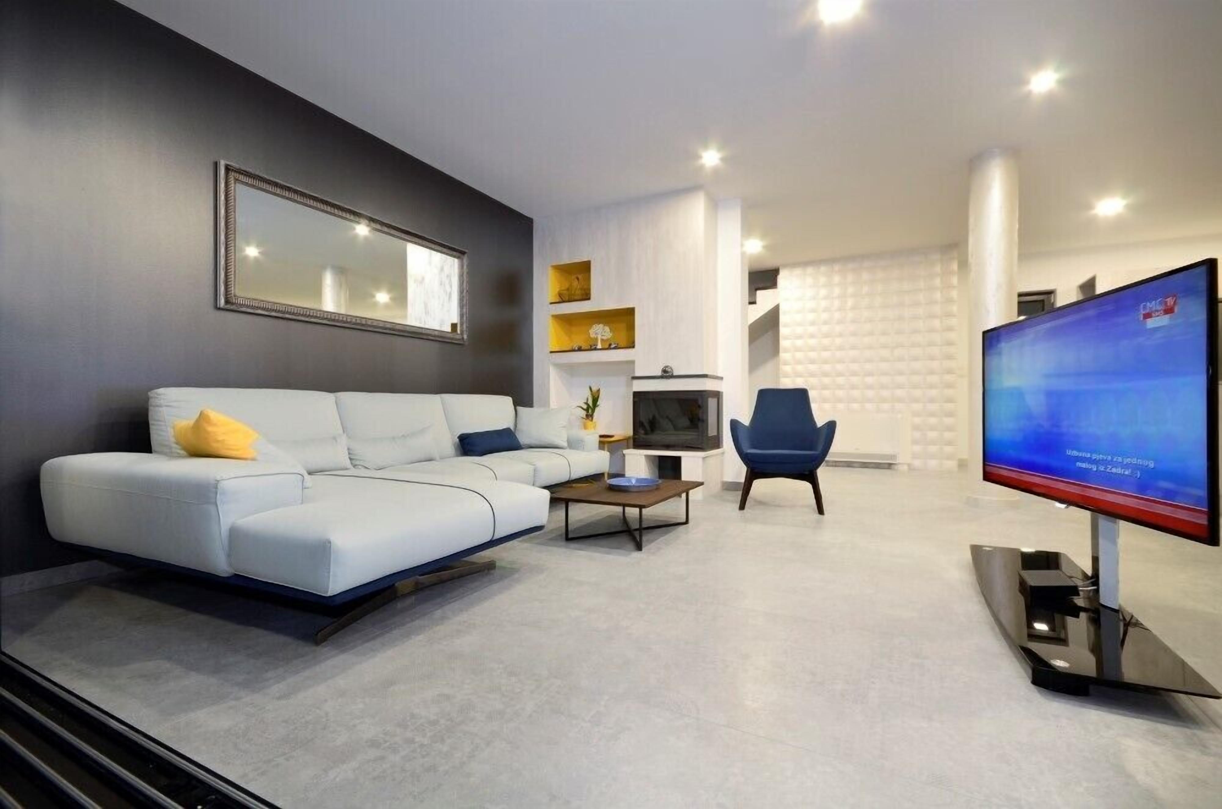 A modern living room with a sofa, a coffee table, a TV, and a chair.
