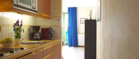 Una cocina con microondas, cafetera y lavamanos.