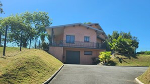 A two-story house with a balcony, a garage, and a sloped driveway.