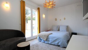 A bedroom with a bed, a sofa, a small table, and a ceiling light fixture.