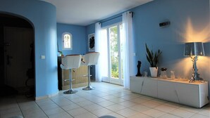 A modern kitchen with white cabinets, a built-in oven, and a window overlooking a garden.