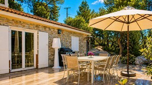 A patio with a table and chairs, a grill, and an umbrella.