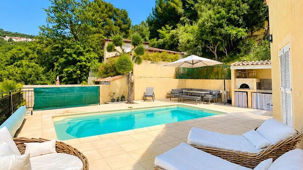 A poolside area with wicker lounge chairs and a barbecue.