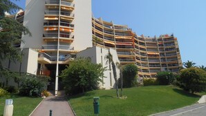 Ein modernes Hotel mit mehreren Balkonen, einem zentralen Eingang und einem gepflegten Rasen.