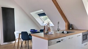 Una cucina moderna con un lucernario, mobili bianchi, un piano di lavoro in legno e un'area pranzo con sedie blu.
