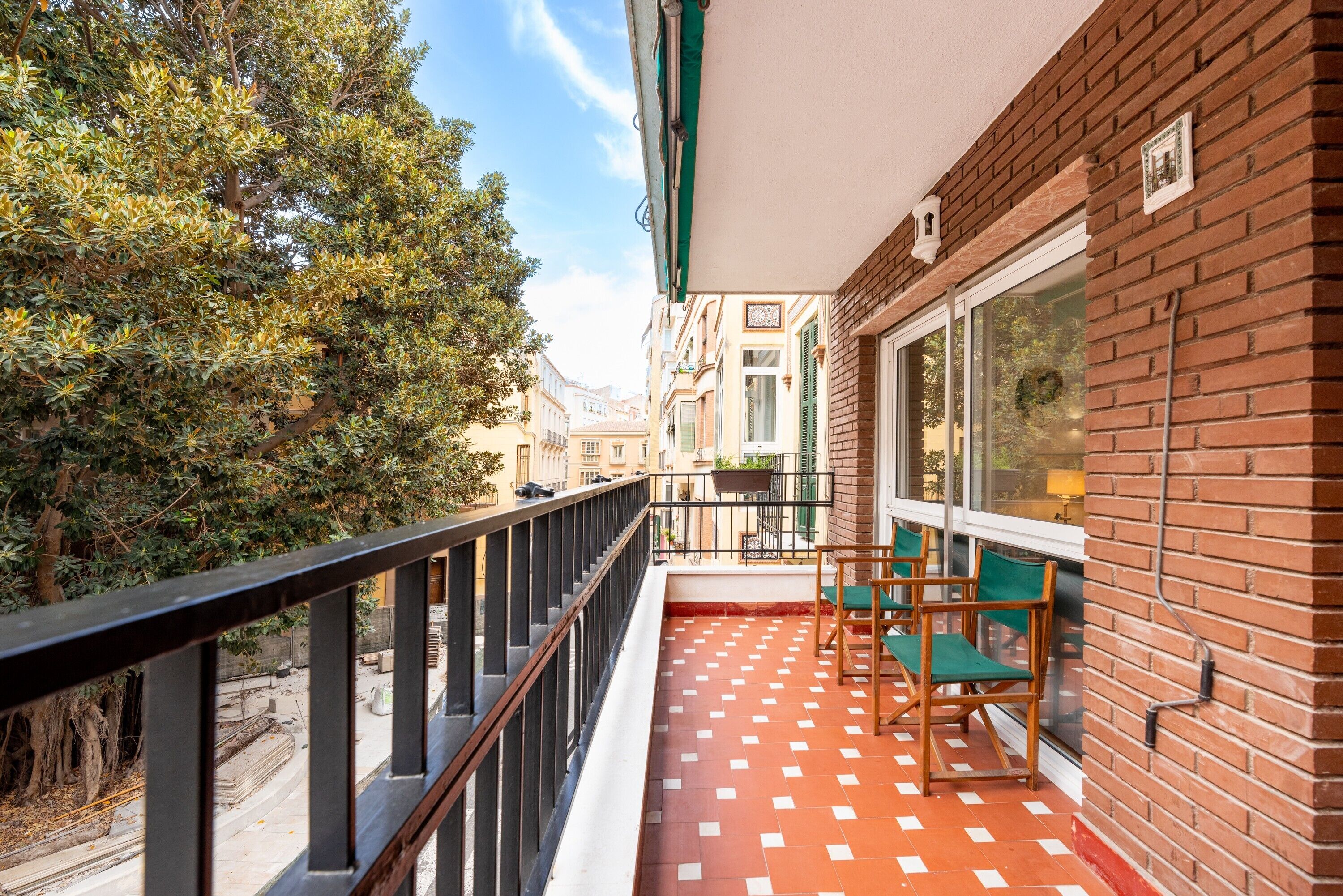 A balcony with a tiled floor, a railing, and two green chairs.