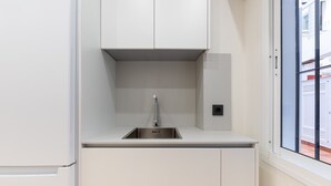 Una cocina moderna con un lavamanos de acero inoxidable, armarios blancos y un ventanal con vistas al exterior.