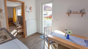 Una cucina compatta con zona pranzo, un termosifone, una finestra vista e un piccolo ripiano con oggetti decorativi.