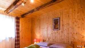 A cozy wooden room with a bed, a nightstand, and a lamp.