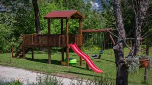 A wooden play structure with a red slide in a park.