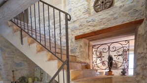 Un escalier en pierre avec une rampe en fer forgé menant à un palier.