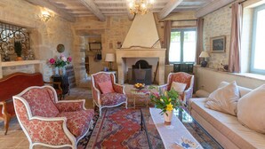 Une pièce chaleureuse avec une cheminée, des fauteuils à motifs floraux, un canapé et un tapis décoratif.