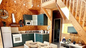 Eine moderne Küche mit Holzwänden, eine Essecke mit Tisch für vier Personen und eine Treppe, die in einen oberen Bereich führt.