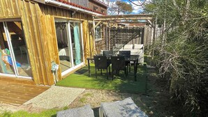 Ein Holzhaus mit Terrasse, einem Tisch mit Stühlen und einer überdachten Sitzgelegenheit.