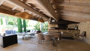 An outdoor patio with a stone fireplace, a dining table, and several chairs.