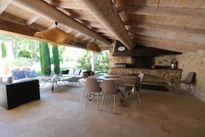 Un patio al aire libre con chimenea de piedra, una mesa de comedor y varias sillas.