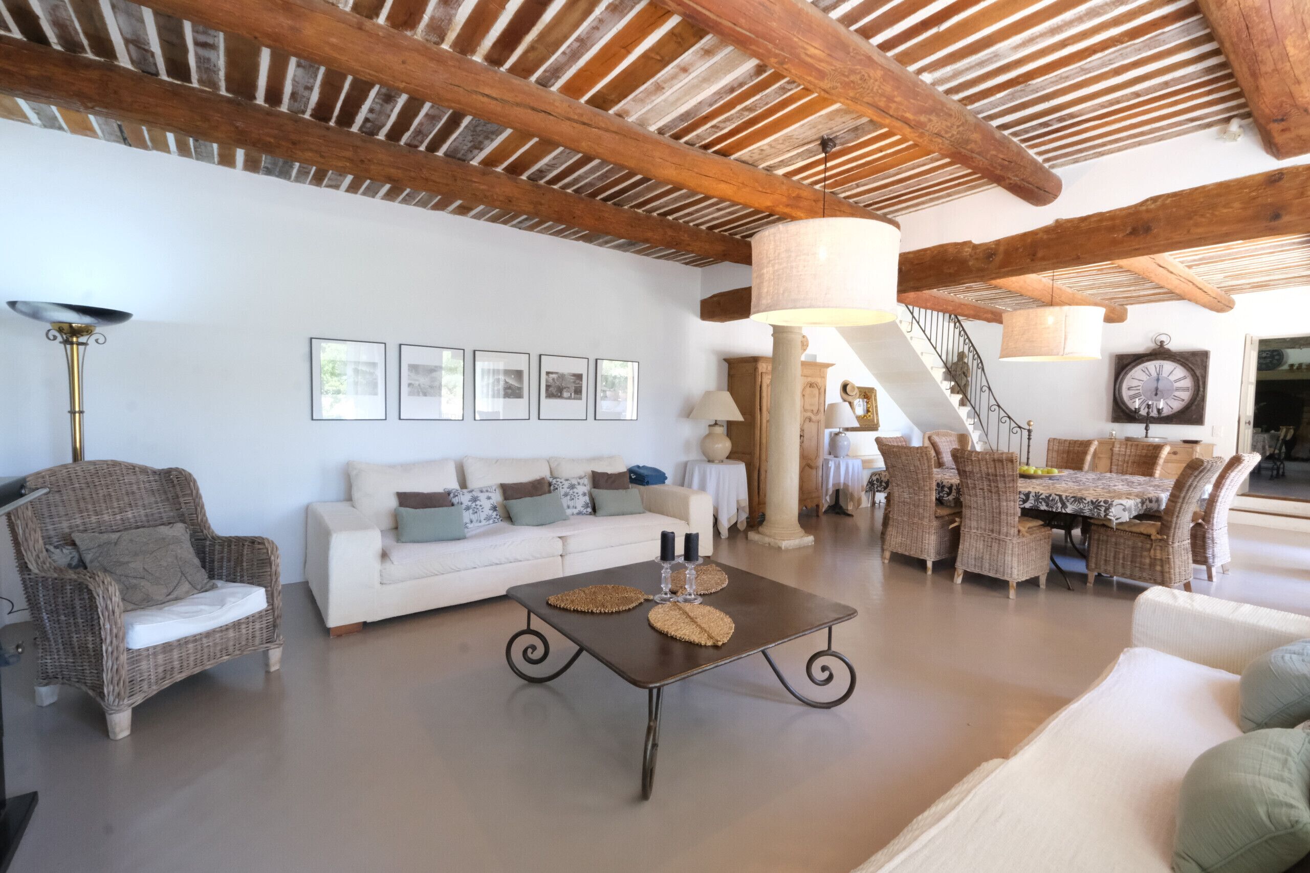 Un vaste espace de vie doté d’un plafond haut, une table à manger pour quatre personnes et un escalier menant à un autre niveau.