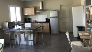 A modern kitchen with a central island, wooden cabinets, a stainless steel range hood, and a refrigerator. - PROVENCAL STYLE HOUSE WITH SEA VIEW (Calenzana)