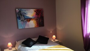 A neatly made bed with a yellow throw, two black pillows, and a painting above it. There are two bedside lamps on white nightstands. - PROVENCAL STYLE HOUSE WITH SEA VIEW (Calenzana)