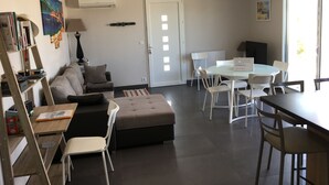 A modern living room with a sofa, ottoman, and a dining area with a table and chairs. - PROVENCAL STYLE HOUSE WITH SEA VIEW (Calenzana)