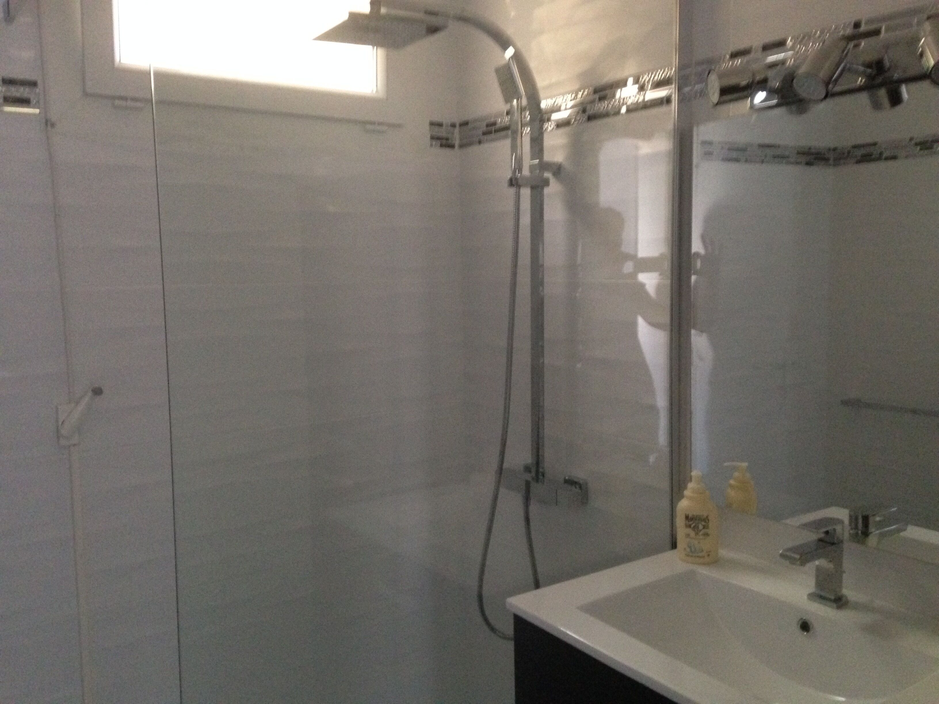 Un baño con cabina de ducha de vidrio, un lavamanos y un espejo.