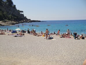 A beach with people sunbathing and swimming.