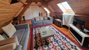 A cozy attic room with a sofa, a coffee table, and a TV.