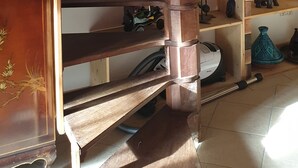 A wooden spiral staircase in a room with a white ceiling and a wooden cabinet to the left.
