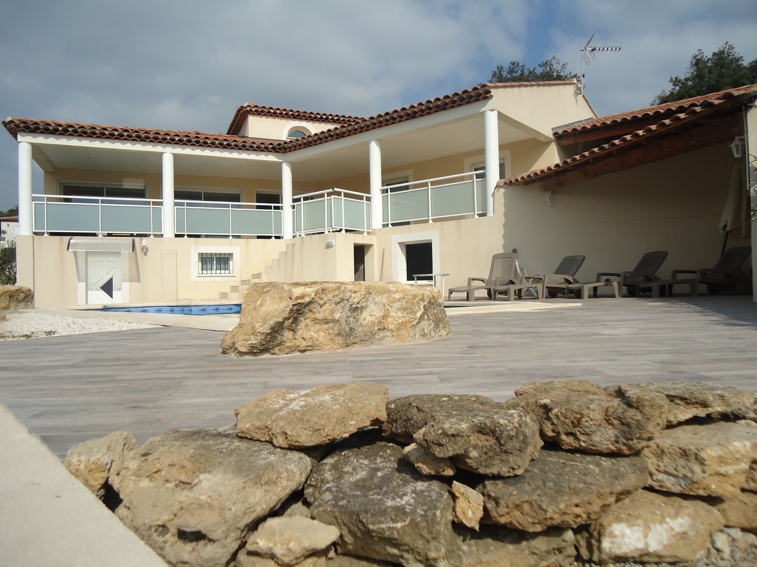 Un bâtiment à deux étages doté d’une piscine, d’un espace extérieur aménagé et d’un parterre rocheux.