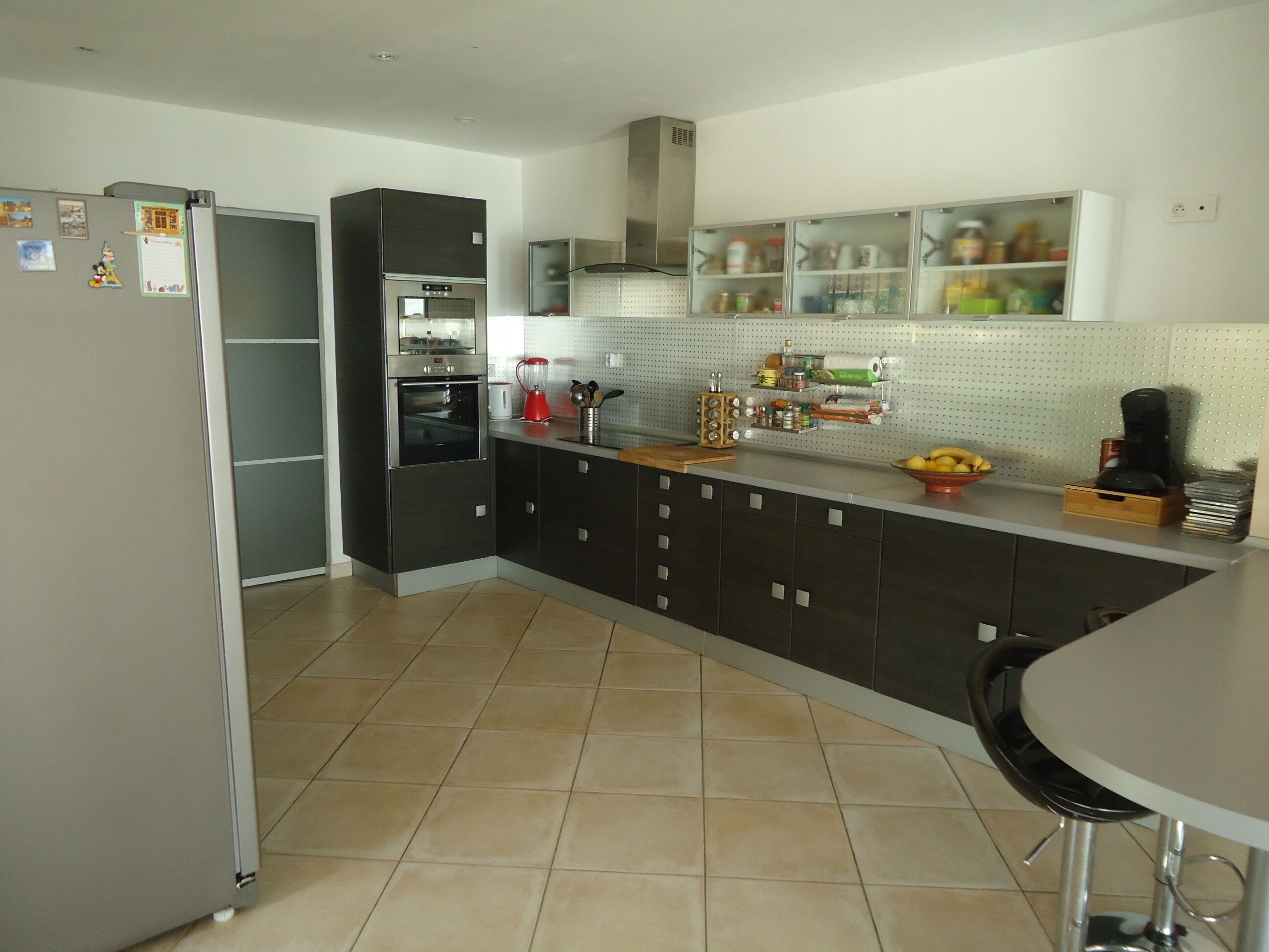 A modern kitchen with a refrigerator, oven, and coffee maker.