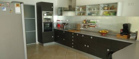 A modern kitchen with a refrigerator, oven, and coffee maker.