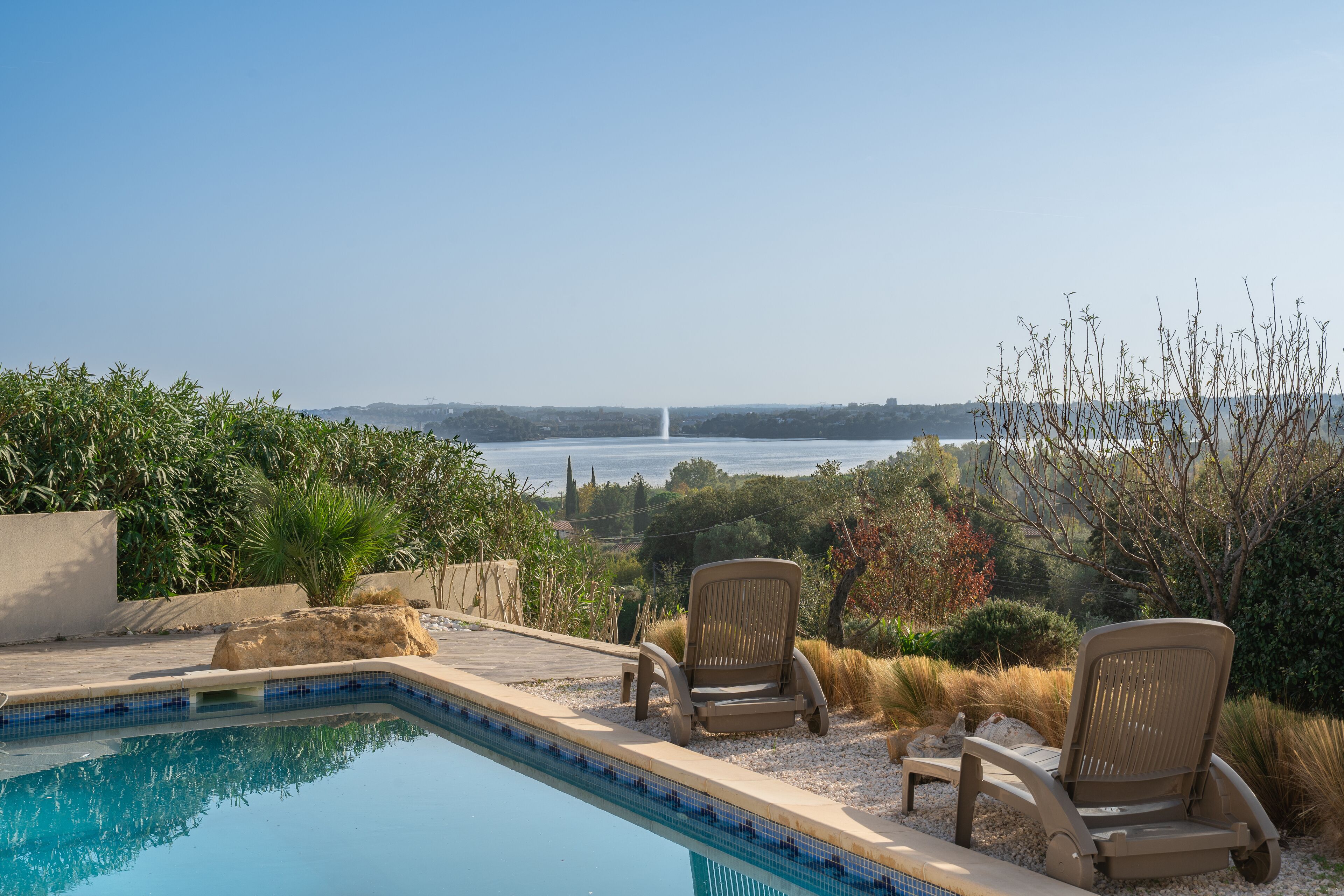A swimming pool with two chairs and a view of a distant fountain.