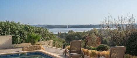 A swimming pool with two chairs and a view of a distant fountain.