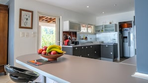 A modern kitchen with a central island, built-in cabinets, and a refrigerator. - A haven of peace nestled in the heart of Provence (Istre)