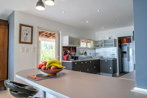 Une cuisine moderne dotée d’un îlot central, de meubles de rangement intégrés et d’un réfrigérateur.
