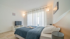 A bedroom with a bed, a TV, a bedside table, and a lamp. - A haven of peace nestled in the heart of Provence (Istre)