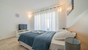 Une chambre à coucher avec un lit, une télévision, une table de chevet et une lampe.