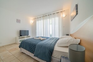 Une chambre à coucher avec un lit, une télévision, une table de chevet et une lampe.