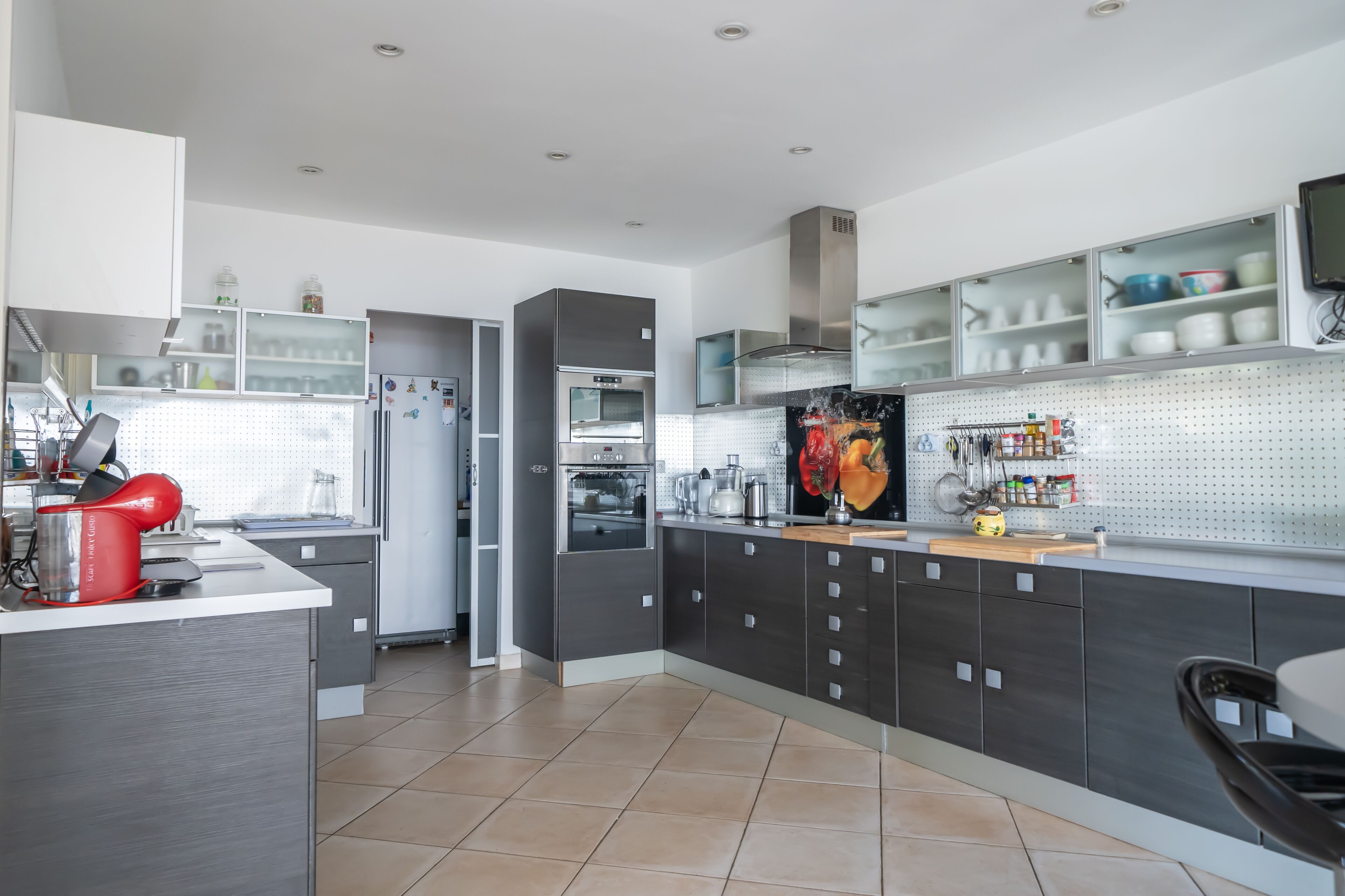 Une cuisine moderne avec des meubles gris, un four en acier inoxydable et un four à micro-ondes.