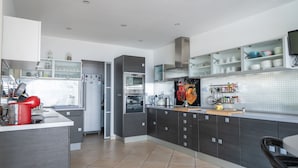 A modern kitchen with grey cabinets, a stainless steel oven, and a microwave. - A haven of peace nestled in the heart of Provence (Istre)