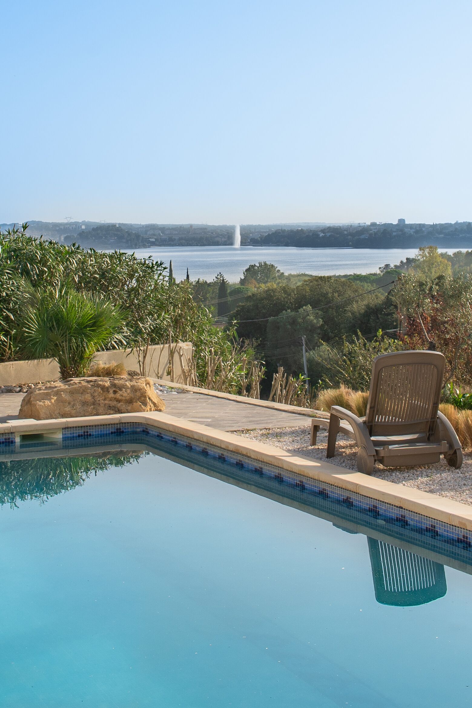A swimming pool with a clear view of a fountain and a body of water in the background.
