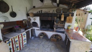 Una cocina rústica con suelo de piedra, un horno de ladrillo y diversos utensilios de cocina.