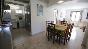 Cocina compacta con electrodomésticos modernos, comedor con mesa y sillas, y sala de estar con sofá y ventana.