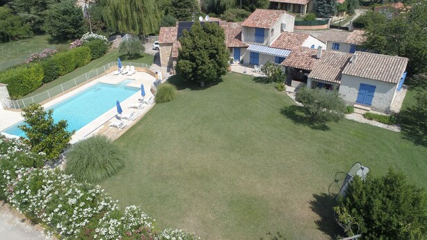 Un barrio residencial con piscina, un amplio césped y casas con techos de tejas.