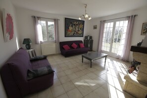 Un salon avec un canapé violet, une table basse et un tableau accroché au mur.