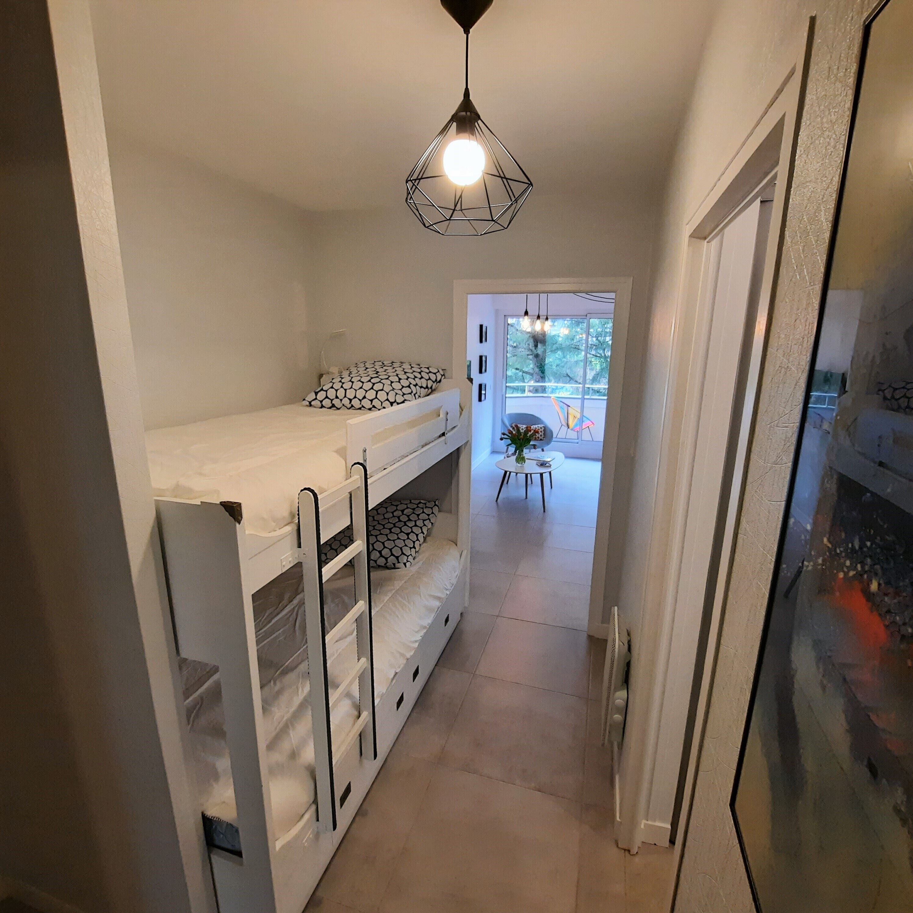 A narrow hallway with bunk beds, a radiator, and a hanging light fixture.