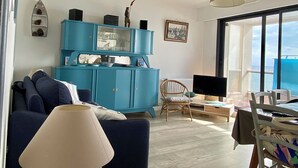 Una sala de estar con un aparador azul, un sofá, una mesa con una lámpara y una silla.