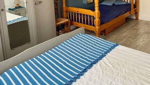 Una habitación con una cama litera, un armario, un escritorio y una silla.